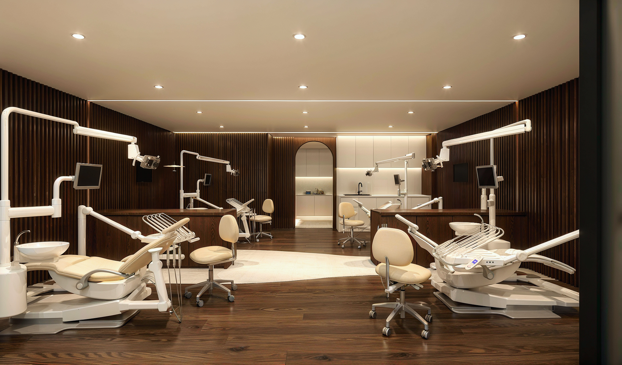 A treatment bay at Miso Orthodontic Studio with walnut slat walls and cream chairs